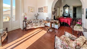 A living room with a sofa, a dining table, and a kitchen area visible through an archway.