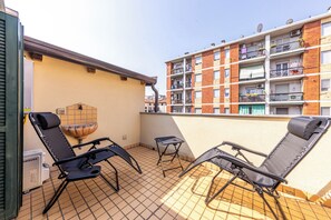 A balcony with two black lounge chairs, a small table, and a water feature. - Luxury Apartment with Terrace - Garibaldi Station (Milan)