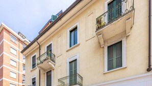 A multi-story building with balconies, a wooden door, and garage doors. - Luxury Apartment with Terrace - Garibaldi Station (Milan)