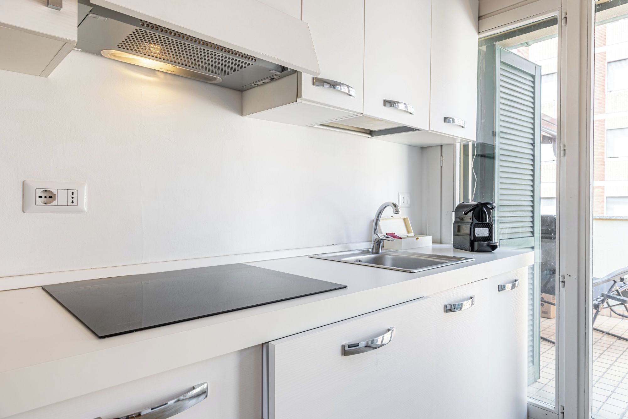 Une cuisine moderne équipée d’une cuisinière intégrée, d’un évier et d’une machine à café.