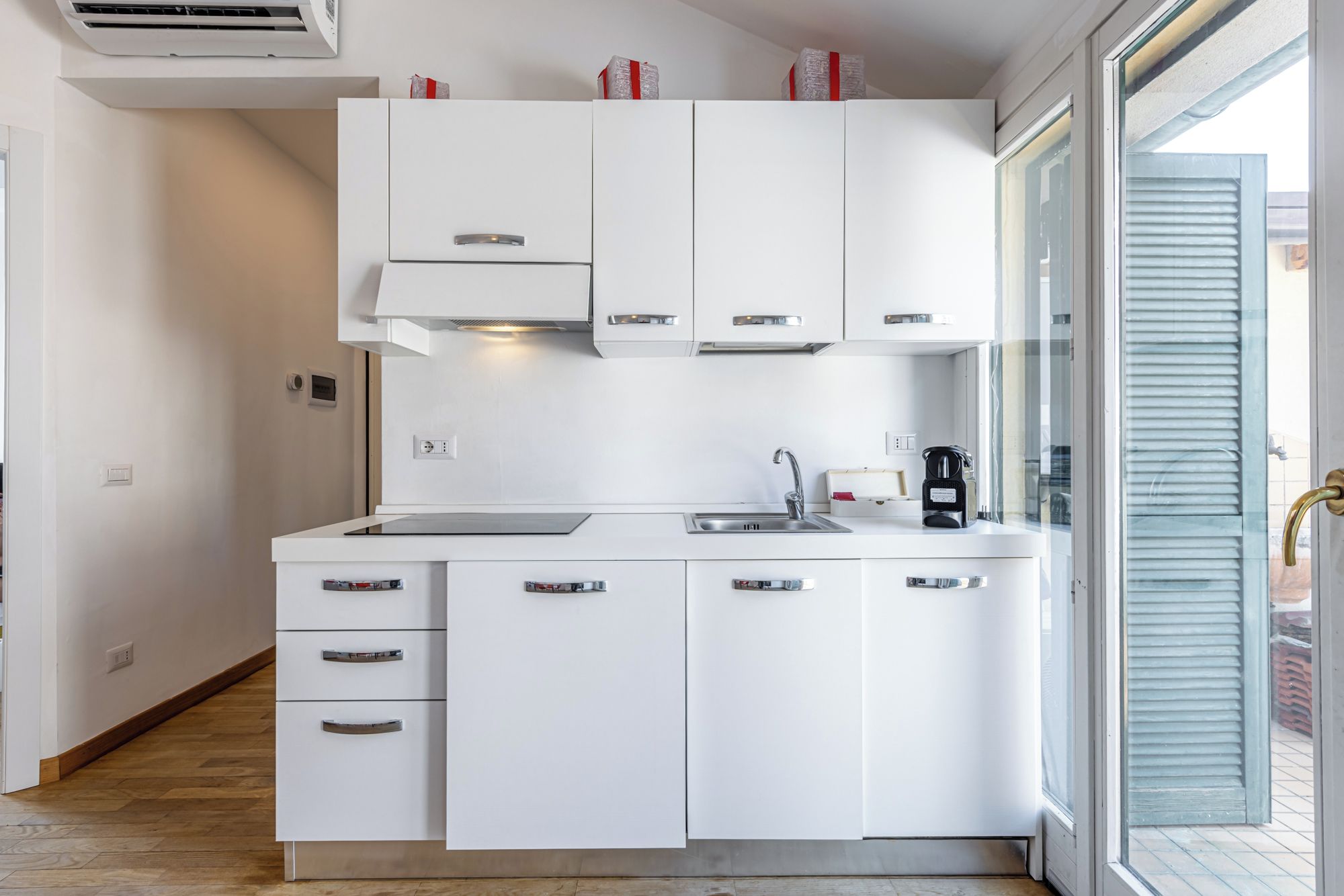 A modern kitchen with white cabinets, a stainless steel sink, and a built-in oven.