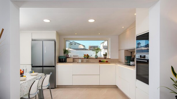A modern kitchen with white cabinetry, a built-in oven, and a dining area with a table and chairs. - Casa Tomodoro - Three Bedroom Villa, Sleeps 6 (Arcos de la Frontera)