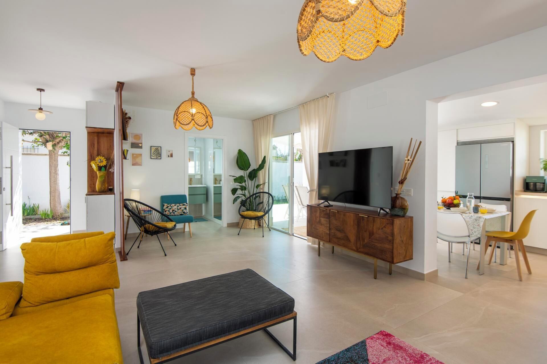 Een moderne woonkamer met een bank, voetenbankje, televisie en een eethoek.