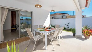 A dining area with a table set for four, outdoor seating, and a view of a building with a tiled roof. - Casa Tomodoro - Three Bedroom Villa, Sleeps 6 (Arcos de la Frontera)