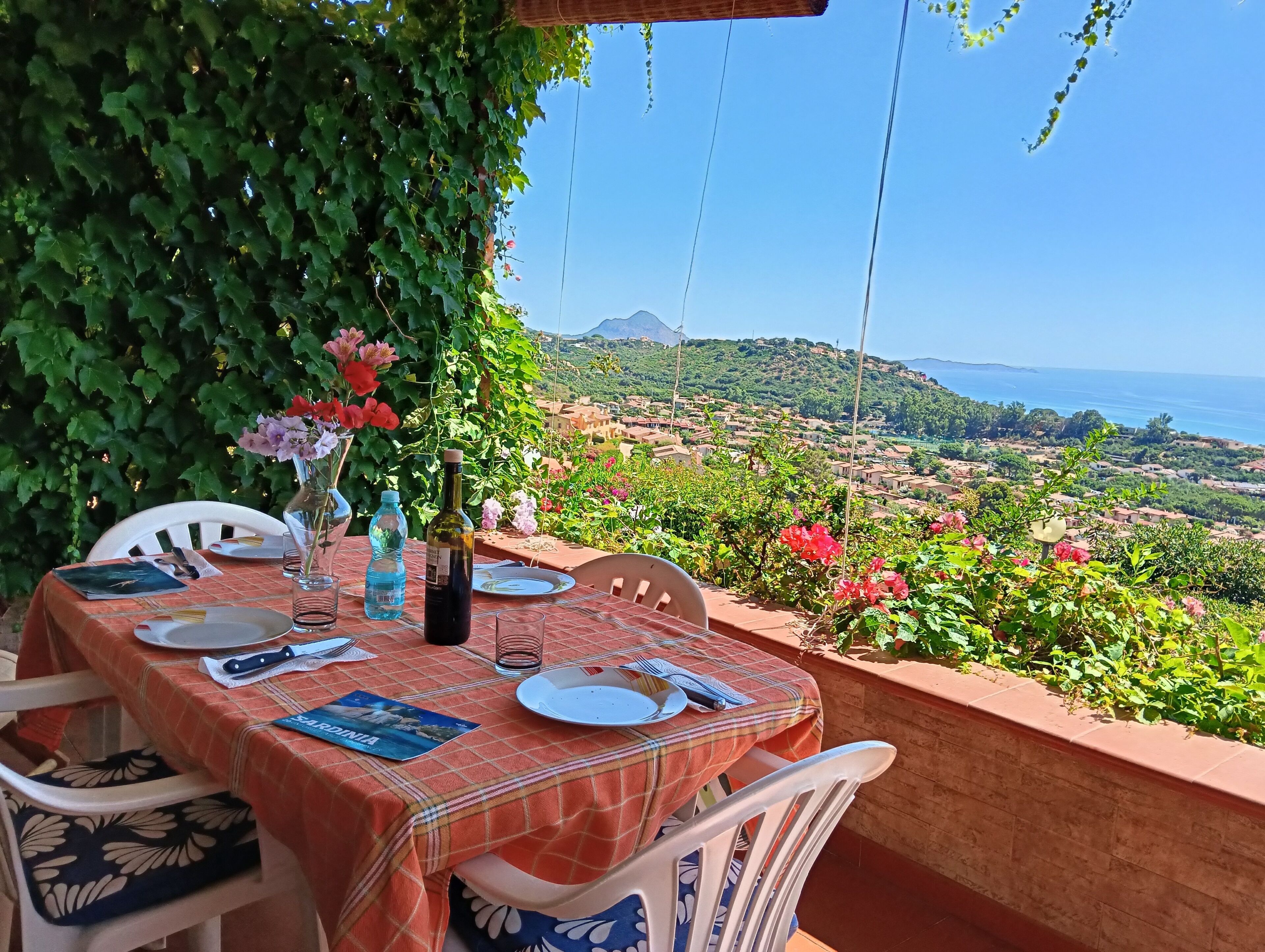 Un tavolo apparecchiato all'aperto con vista su un paesaggio costiero.