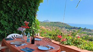 A table set outdoors with a view of a coastal landscape. - Casa Sunshine-Sea View (Costa Rei)