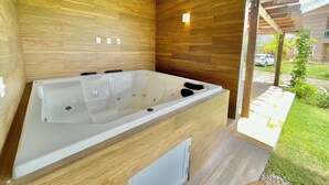 A modern bathroom with a large bathtub, wooden wall panels, and a small window. - Beach house in a beachfront condominium with 3 en-suite bedrooms, Wi-Fi. (Caucaia)