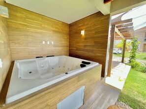 Ein modernes Badezimmer mit einer großen Badewanne, Holzvertäfelung und einem kleinen Fenster.