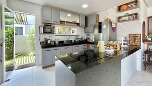 A modern kitchen with a central island, built-in appliances, and a view to a garden. - Beach house in a beachfront condominium with 3 en-suite bedrooms, Wi-Fi. (Caucaia)
