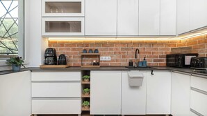 Una cocina moderna con armarios blancos, salpicadero de ladrillo y electrodomésticos integrados.