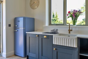 Eine Küche mit einem blauen Kühlschrank, einer weißen Spüle und einem Fenster mit Blick auf Grünflächen.