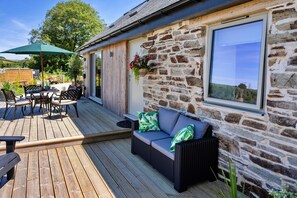 Eine Holzterrasse mit Gartenmöbeln, einer Steinmauer und einem Fenster mit Blick.