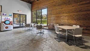 Un espacio interior moderno con pared de madera, una máquina expendedora y un ventanal grande.