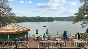 Una terraza con mesas y sillas, con vista a un lago y un bote.