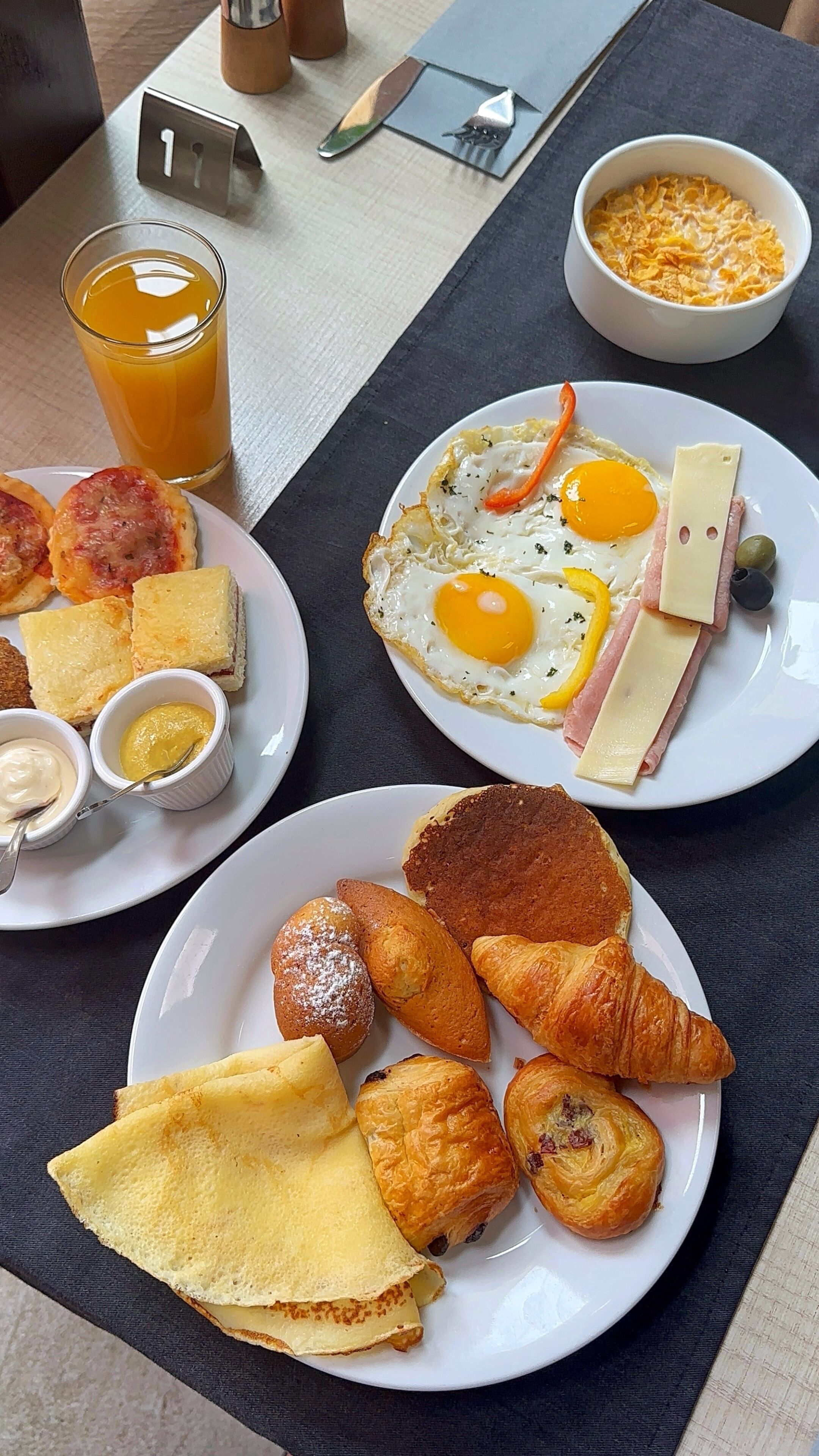 A breakfast setting with plates of food, a glass of orange juice, and a coffee cup.