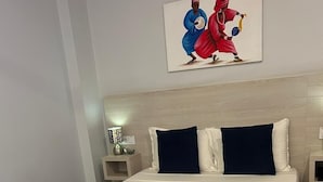 A bed with a white and navy blue bedspread, a wooden headboard, and a painting above.