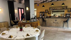 Un restaurante con techo a cuadros, una zona de bar con la marca Khay Gu, y una mesa redonda para cuatro comensales.