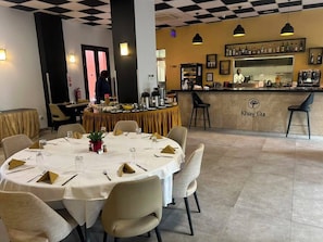 Un restaurante con techo a cuadros, una zona de bar con la marca Khay Gu, y una mesa redonda para cuatro comensales.