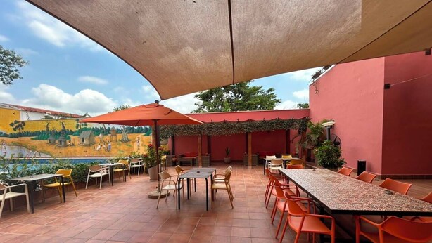 Un patio al aire libre con mesas y sillas, una piscina y un mural en la pared.