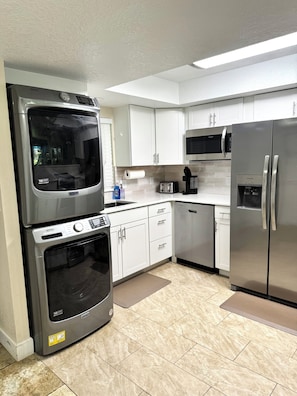 A kitchen with a built-in oven, microwave, and refrigerator, white cabinets, and a tiled floor. - Young Avenue Retreat -Steps to Cocoa Beach (Cocoa Beach)