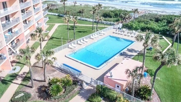 Un hôtel doté d’une piscine, de palmiers et offrant une vue sur l’océan.
