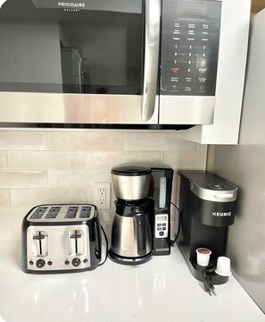 Eine Küche mit einer Frigidaire-Mikrowelle, einem Toaster, einer Kaffeemaschine und einem Keurig-Kapselspender.