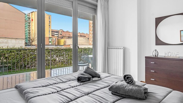 Une chambre avec une grande fenêtre, un lit, une commode et un miroir.