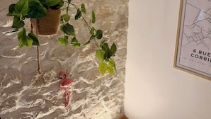 Tekstuuripintainen seinä, jossa on roikkuva kasvi ja flamingoaiheinen koriste.