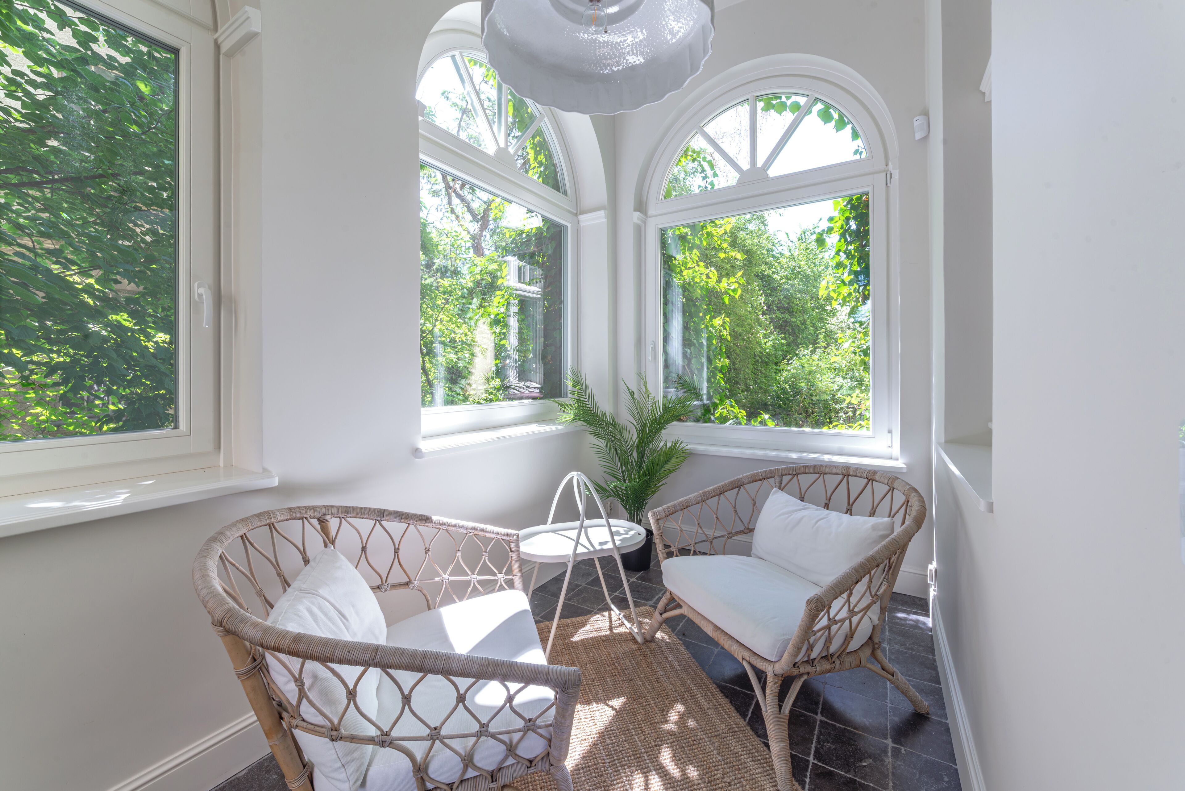 A sunroom with wicker furniture, a small table, and a potted plant.