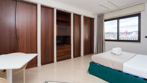 A hotel room with a bed, a desk, a TV, and a view of the city. - Triple G Rooftop 105 By Dimorra  (Naples)