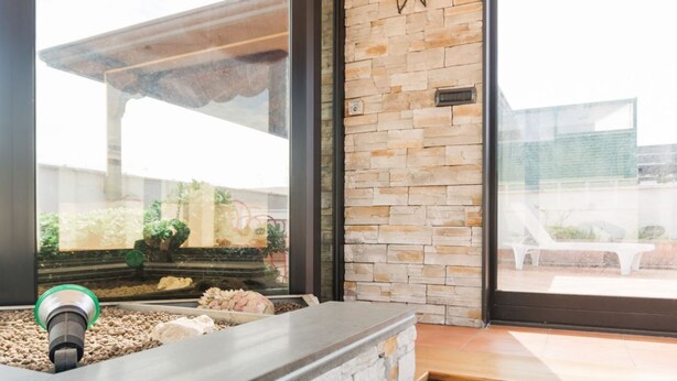 A reception area with a stone wall, a reception desk, and a view through a large window. - Triple G Rooftop 105 By Dimorra  (Naples)