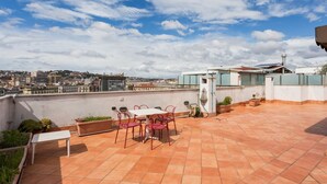 A rooftop terrace with a table and chairs, potted plants, and a view of the cityscape. - Triple G Rooftop 105 By Dimorra  (Naples)