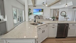 A kitchen with a large island, stainless steel appliances, and a view of the outdoors. - Villa Vivara, Stylish 4BR Villa with Heated Pool (Cape Coral)