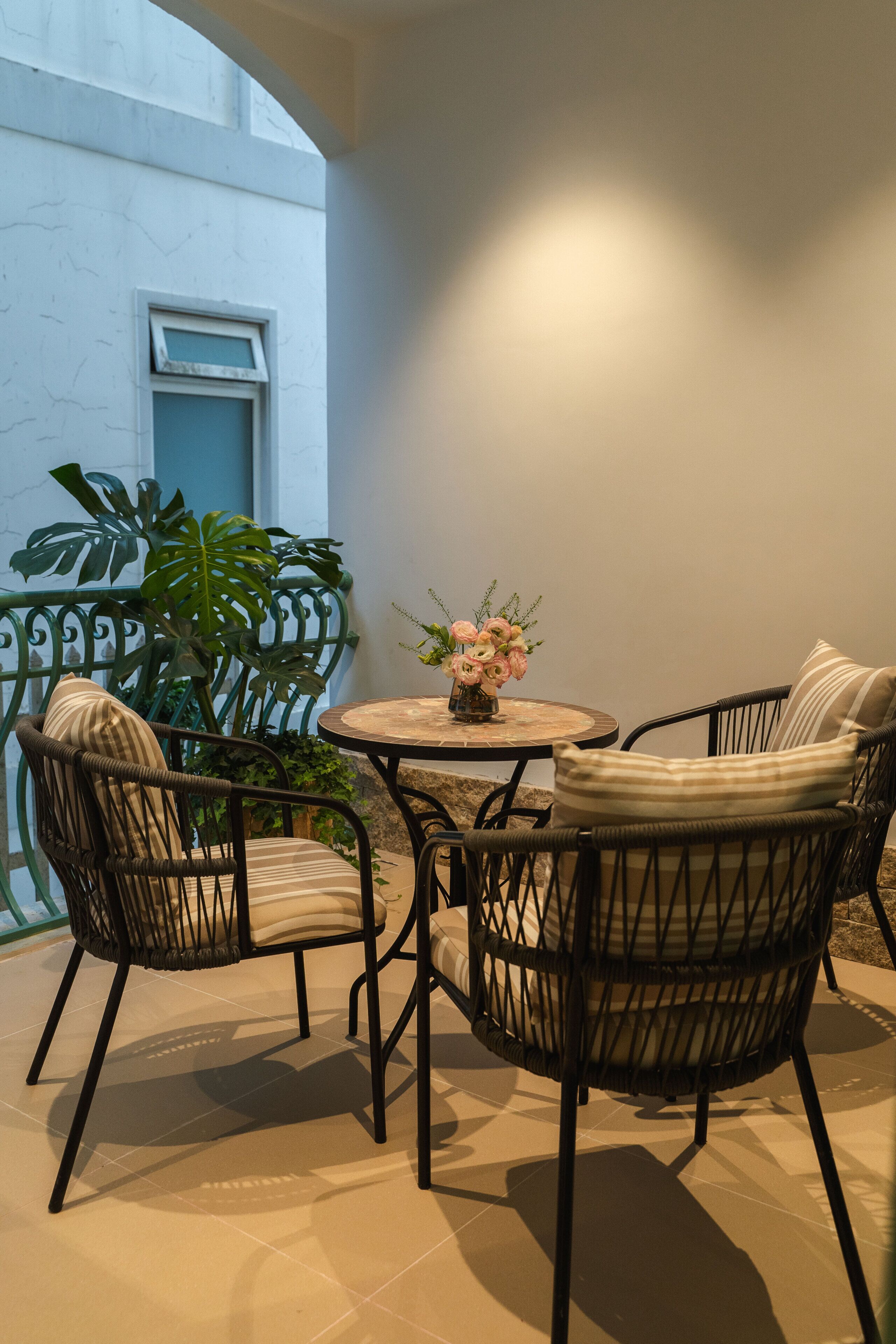 Een terras met rieten meubels, een ronde tafel en een plant in pot.