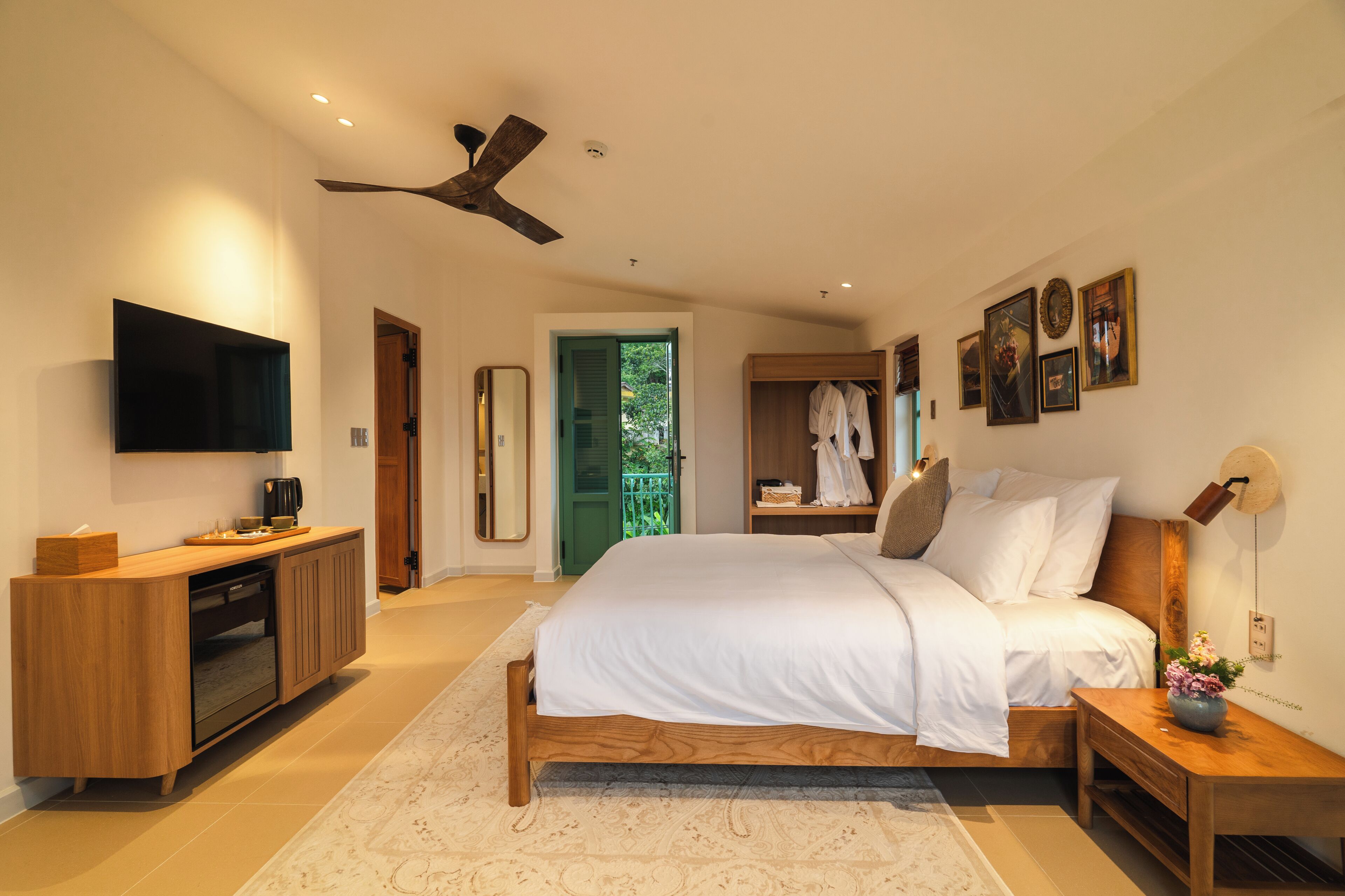 A modern bedroom with a bed, bedside tables, a TV, and a ceiling fan.