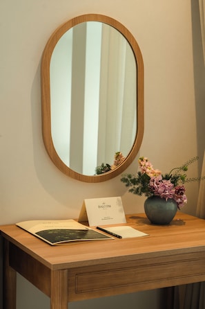 Un escritorio de madera con un espejo, un florero con flores y una tarjeta de bienvenida.