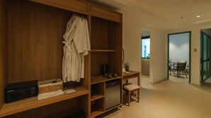 Una habitación con un armario de madera, una mesita con un florero y un banco.