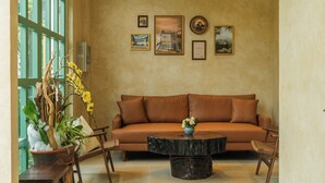 Una sala de estar con un sofá marrón, una mesita de centro y una planta en maceta con flores amarillas.