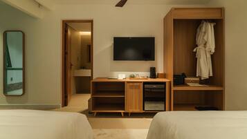 A hotel room with two beds, a desk with a flat-screen TV, a wardrobe, and a mirror.