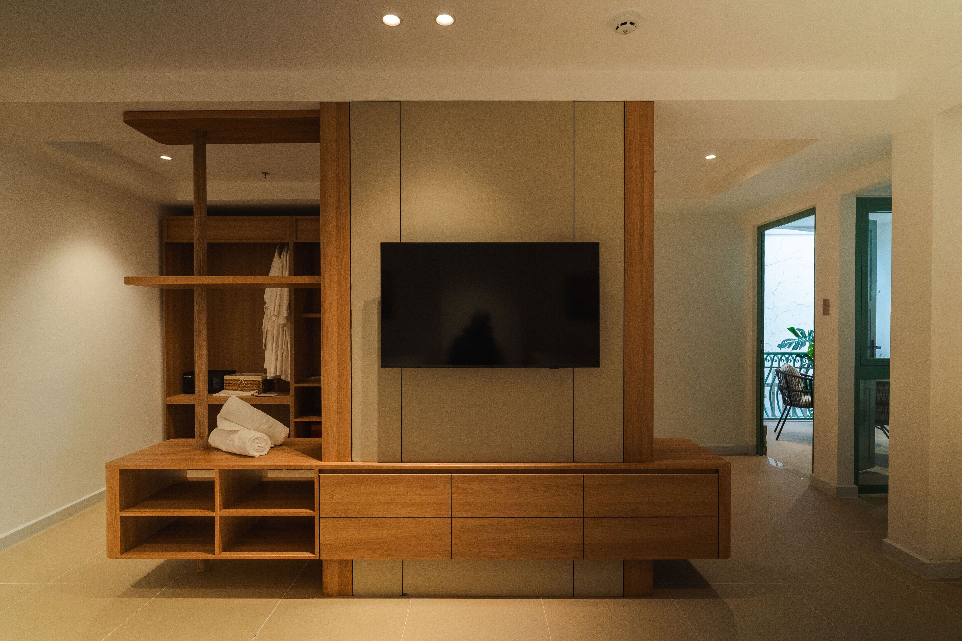 Una sala moderna con un televisor de pantalla plana montado en la pared, estanterías de madera y un mueble empotrado para entretenimiento.