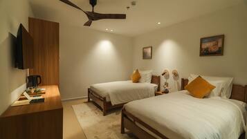 A bedroom with two beds, a ceiling fan, a coffee maker, and a painting on the wall.