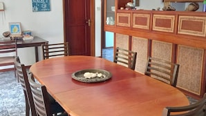 Un comedor con una mesa y sillas de madera, un aparador decorativo con paneles trenzados y una puerta con marco de madera.