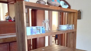 Una mesa de madera con un estante superior que contiene una jarra, tazas y un objeto decorativo con la palabra 'LOVE'.