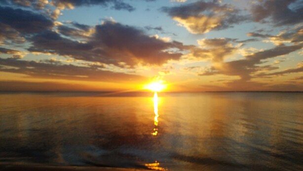 A sunset over a calm sea with a clear horizon.
