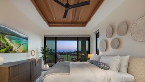 Een slaapkamer met een groot bed, een plafondventilator, uitzicht op de omgeving, en een eethoek met uitzicht.