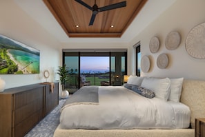 Ein Schlafzimmer mit einem großen Bett, einem Deckenventilator, Blick ins Freie und einem Essbereich mit Aussicht.