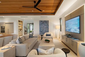 Un salon moderne comprenant un canapé, des fauteuils, une table basse et un téléviseur.
