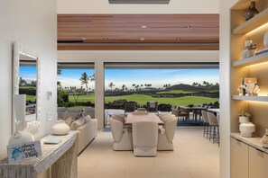 Un intérieur moderne comprenant un coin repas, une vue sur un terrain de golf et un comptoir d’accueil.