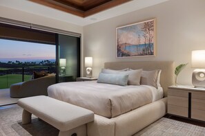Ein modernes Schlafzimmer mit einem großen Bett, einer Bank, einem Nachttisch mit Lampe und Blick auf einen Golfplatz.