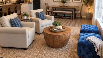 A modern living room with a sofa, armchairs, a coffee table, and a dining area with a table and chairs.
